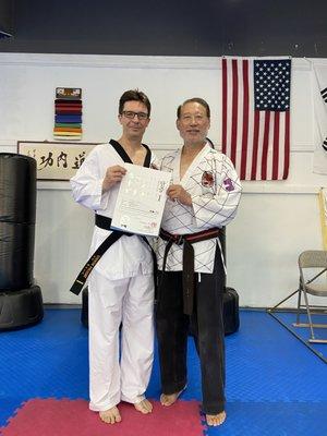 Student receiving black belt promotion certificate.