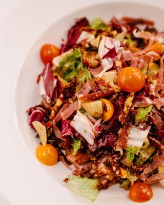 Lola Rosa Salad is our take on the Antipasta Salad with with prosciutto, salami, olives, & artichokes.