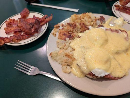 Eggs Benedict with home fries and a side of bacon