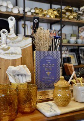 Charcuterie boards, glassware, a honey pot with dipper, and a book on bees.