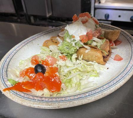 Taquitos shredded beef or chicken rolled up in corn tortillas garnished with sour cream and guacamole