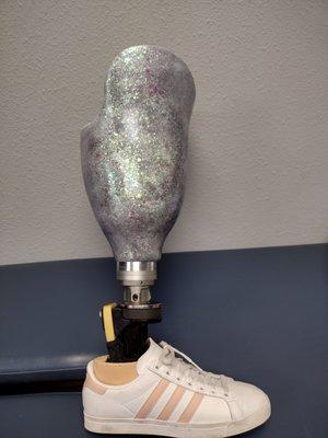 This is an iridescent glitter prosthetic socket with a variety of blues, pink, silver, and green.