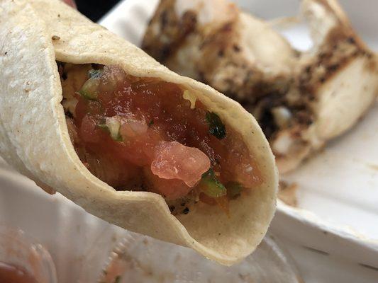 Chicken wrapped inside corn tortilla and some pico de gallo