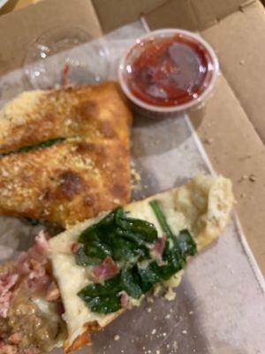 Spinach stuffed Calzone with a side of tablespoon measure of marinara