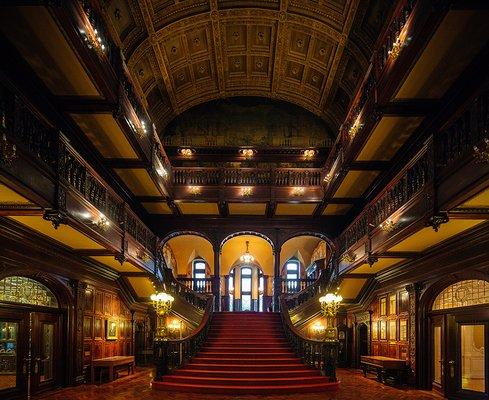 The Grand Hall, which features twin grand fireplaces and mantels and rises three stories to a gilded, barrel-vaulte.