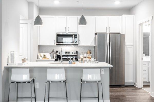 Crisp kitchen with stainless appliances, backsplash and granite countertops.