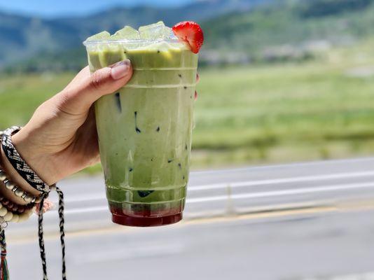 Finely ground matcha with strawberry-rose syrup, topped with oat milk over ice.