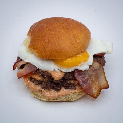 Egg & Bacon Burger served on warm potato bun. Fly sauce inside.