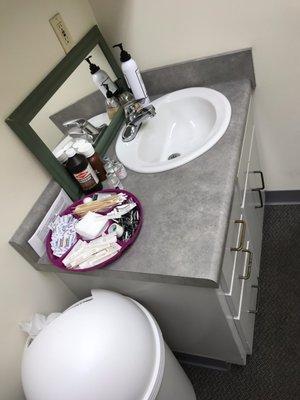 Sink area in exam room. Also note the trash can opening facing the wall and overflowing.