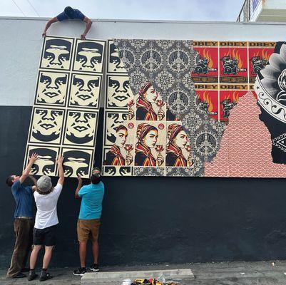 The IA team installing a custom mural donated by Shepard Fairey on the outside of Resin