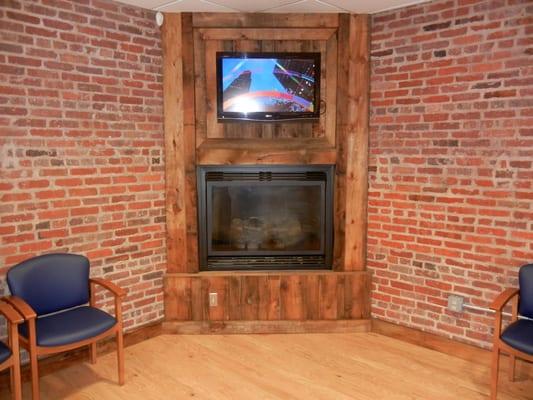 A closeup of the fireplace, TV, and beautiful original brick walls in our waiting room.