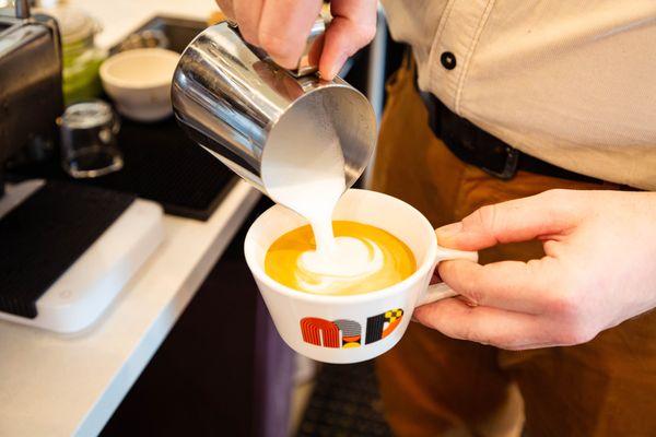 SMIMD barista pouring a latte.