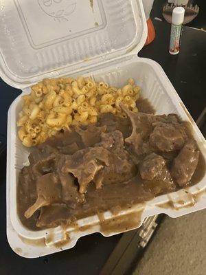 Ox tail with gravy sauce on top of white rice w side of Mac n cheese.