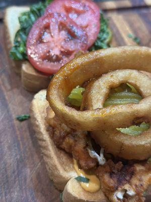 The building of my Sriracha chicken, tender sandwich with onion rings