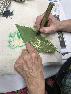 Student at Macon Co Art Asso. paints leaves.