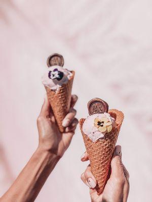 Two plant-based strawberry ice cream cones by our peacock mural!