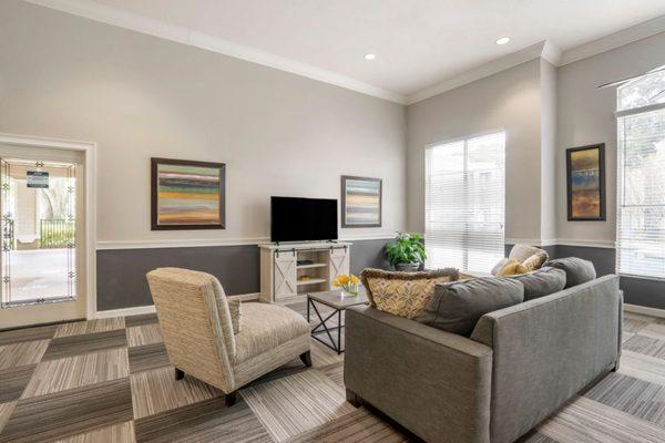 Clubhouse lounge with couch, chair, coffee table, television, and large window for natural lighting