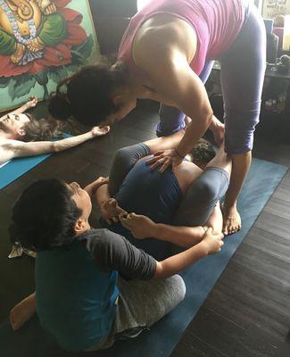 Krista and her son Kaiden adjusting a student in Supta Kurmasana