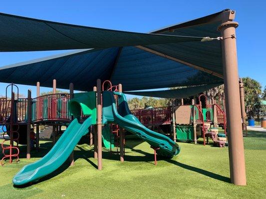 Huge covered and fenced in playground with turf.