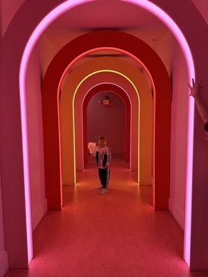 A boy and his cotton candy in lit arches.