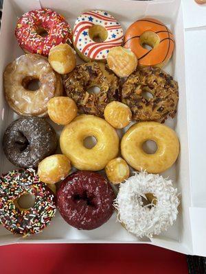 A dozen donuts with some donut holes thrown in as a bonus