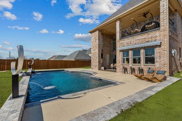 Enjoy a breathtaking view of your custom geometric pool that features a beautiful water feature, adding a touch of elegance to your backyard