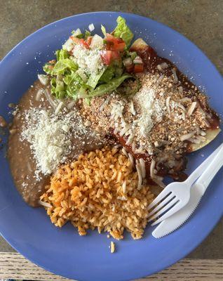 Chicken enchiladas with red sauce, rice, and refried beans