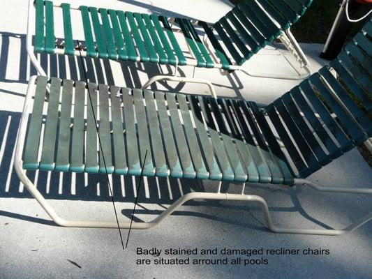 Badly stained and damaged recliner chairs are situated around all pools