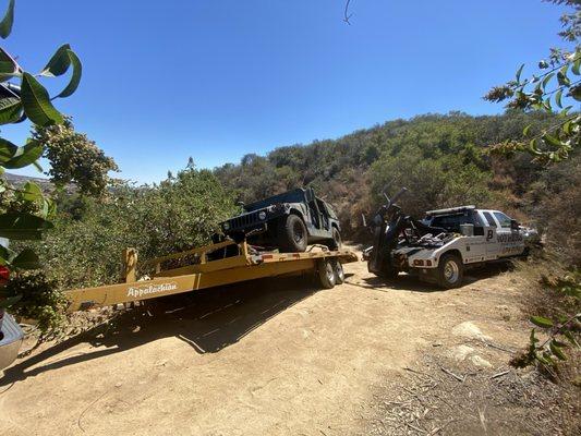 Brothers towing pulling out a 30' trailer carrying a Humvee from side of cliff