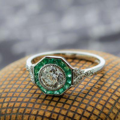 Vintage inspired platinum diamond ring accented with an emerald halo