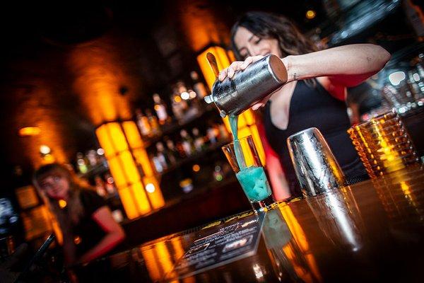 This is a photo of one of our amazing bartenders. She's serving a delicious cocktail to a customer.