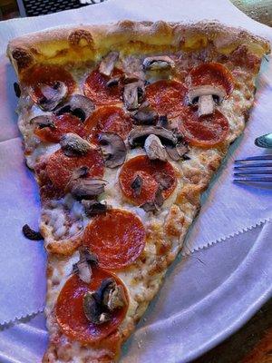 HUGE slice of pepperoni pizza with mushrooms.