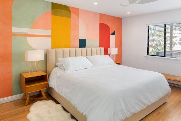 Midcentury modern furniture such as the bedside tables complement the wall mural.