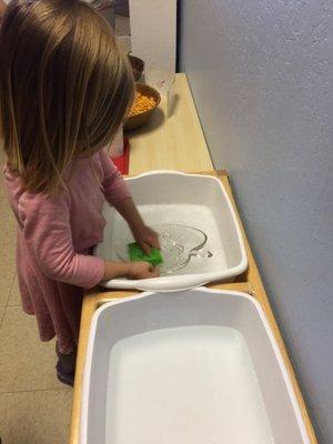 A student washing their own dishes in Practical Life.