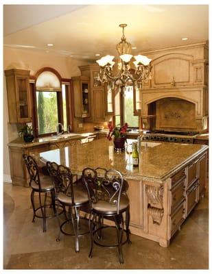 A kitchen in a custom home designed by Mega Builders; custom hood, island with hidden lift, cabinets clear both sides at window