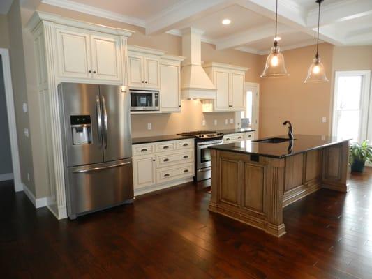 Open floorplan design with white glazed cabinetry, warm accent stained glazed island & granite tops.