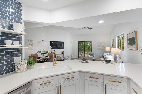 An all white kitchen gets a pop of color with navy blue tile and gold accents