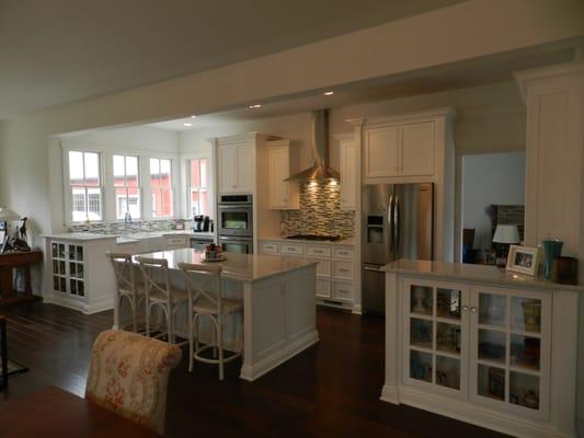 Open floorplan design with white cabinetry, glass tile backsplash & marble tops.