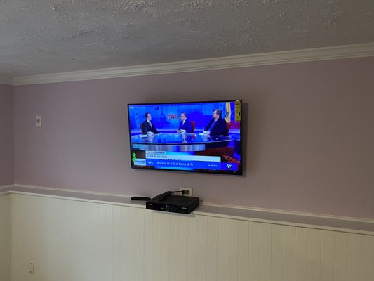 Tv mounted on a wall in a basement with wire concealment.