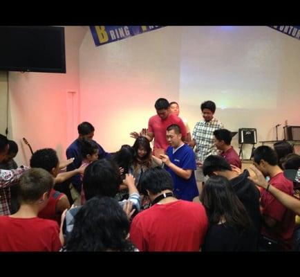 Praying for a birthday celebrant during youth service.