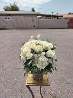 White arrangement with seeded eucalyptus in a beautiful iridescent green vase