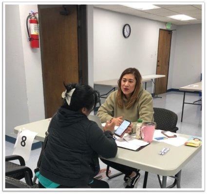 IILA case manager (green sweater) helps enroll a client in needed services for food and more.