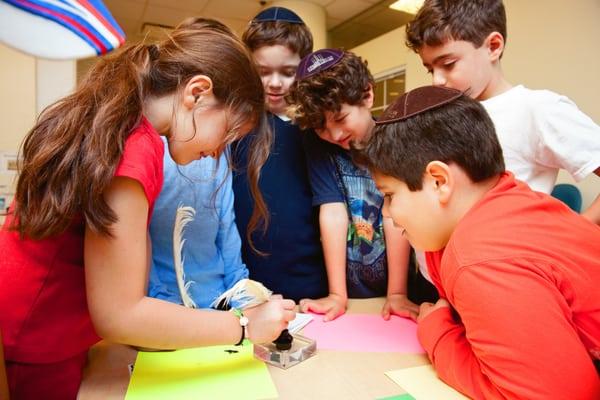 Children learn about the mezuzzah and practice writing with a quill and parchment.