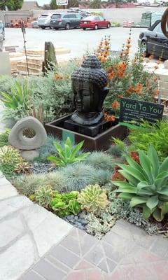 I love the mixture of Asian-themed fountain and art placed along side succulents and flowering plants.