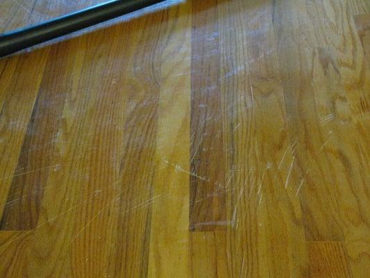 Floor had scratches, nail holes, and stains before treatment.