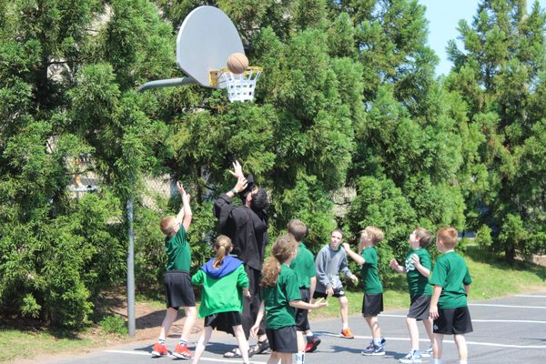 Father David playing basketball with students at recess.