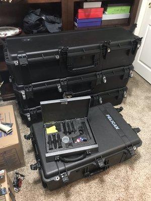 Metal briefcase with custom foam sitting on handgun case in front of 3 rifle cases.