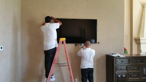 Two of our technicians preparing a TV installation inside of a motorized artwork frame.