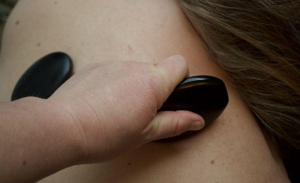 A hot stone is used as a scraper on the Upper Trapezius muscle.