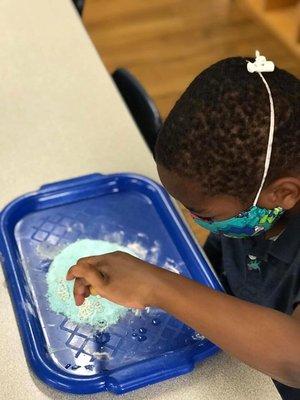 My son doing a science experiment: making fizzing "Olympic rings" out of baking soda and vinegar.